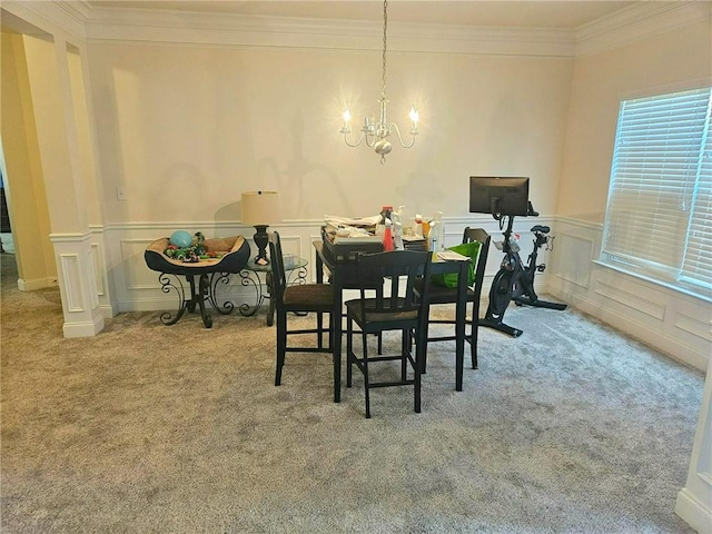 dining room featuring carpet floors, crown molding, a chandelier, a wainscoted wall, and a decorative wall