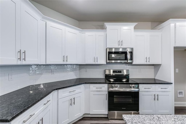 kitchen with appliances with stainless steel finishes, white cabinetry, and dark stone counters