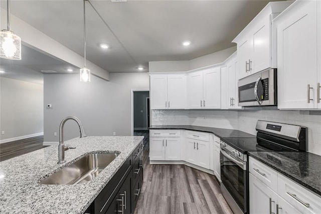 kitchen with white cabinetry, sink, stainless steel appliances, backsplash, and decorative light fixtures