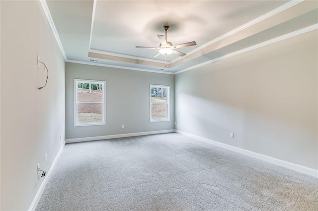 carpeted spare room with ceiling fan, crown molding, and a tray ceiling