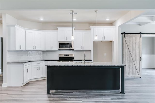 kitchen with a barn door, sink, range, and a kitchen island with sink