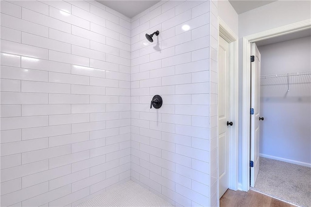 bathroom with a walk in closet, tiled shower, and wood finished floors