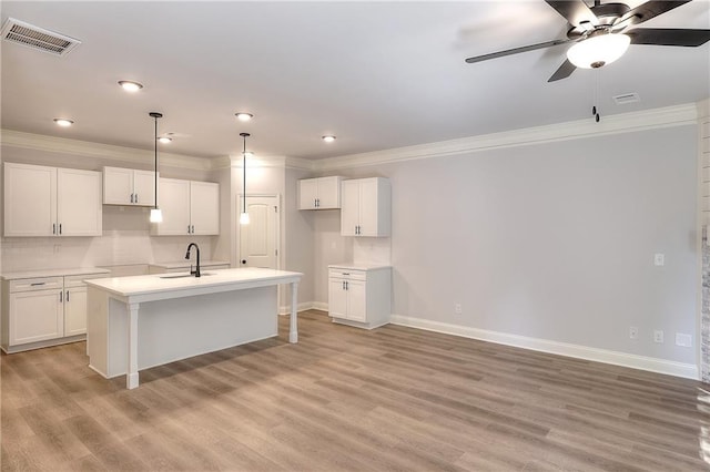 kitchen featuring visible vents, white cabinets, light wood-style floors, and a kitchen island with sink