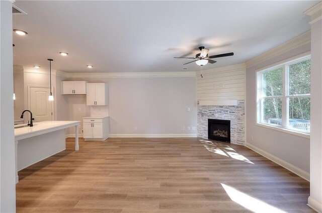 unfurnished living room with ornamental molding, a fireplace, ceiling fan, and hardwood / wood-style floors