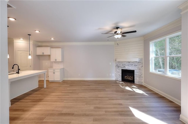 unfurnished living room featuring crown molding, baseboards, and light wood-type flooring