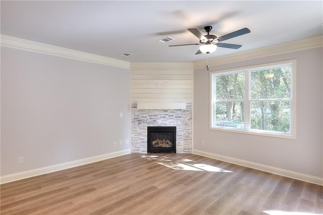 unfurnished living room with baseboards, light wood-style flooring, a fireplace, ceiling fan, and ornamental molding