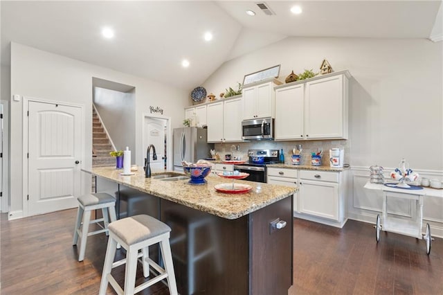 kitchen with appliances with stainless steel finishes, a kitchen island with sink, and white cabinets