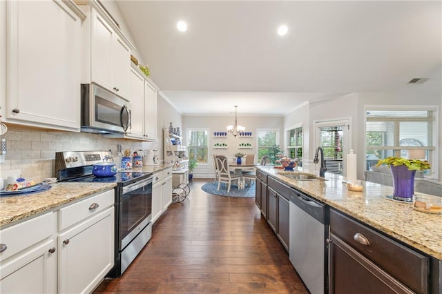 kitchen featuring pendant lighting, sink, white cabinetry, backsplash, and stainless steel appliances