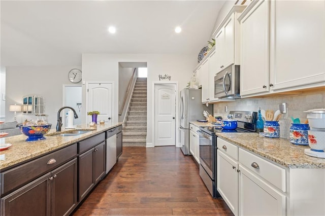 kitchen with sink, white cabinets, stainless steel appliances, light stone countertops, and backsplash