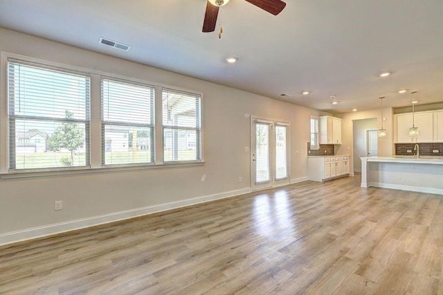 unfurnished living room featuring light hardwood / wood-style floors, ceiling fan, and sink
