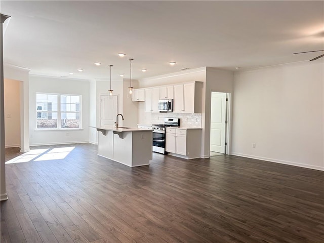 kitchen featuring dark hardwood / wood-style floors, decorative light fixtures, a kitchen island with sink, appliances with stainless steel finishes, and ornamental molding