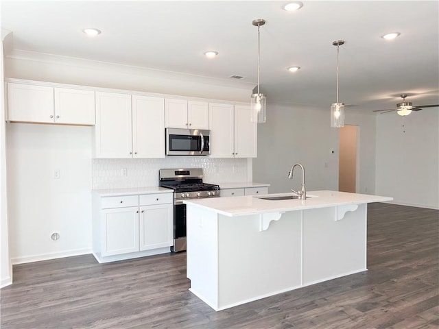 kitchen with white cabinetry, sink, hanging light fixtures, an island with sink, and appliances with stainless steel finishes