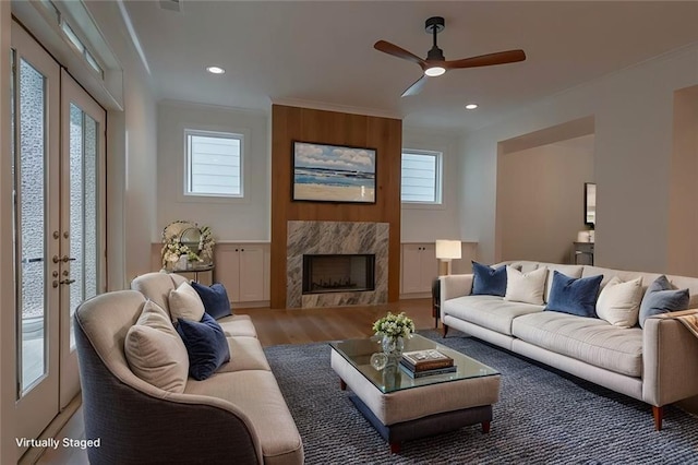 living room featuring crown molding, a premium fireplace, ceiling fan, wood-type flooring, and french doors