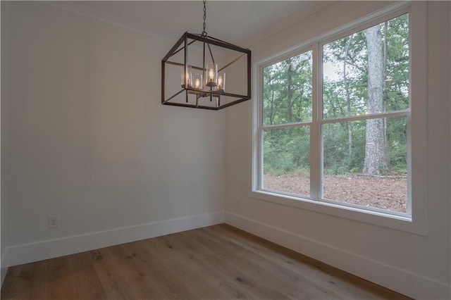 unfurnished dining area with hardwood / wood-style flooring, an inviting chandelier, and a wealth of natural light