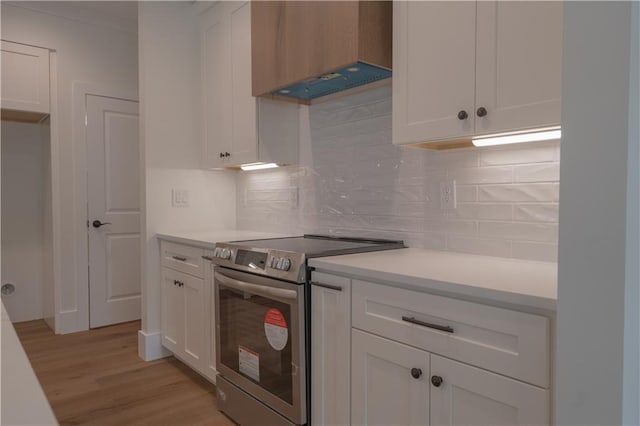 kitchen with white cabinetry, backsplash, electric range, and custom range hood