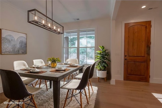 dining space featuring crown molding and light hardwood / wood-style floors