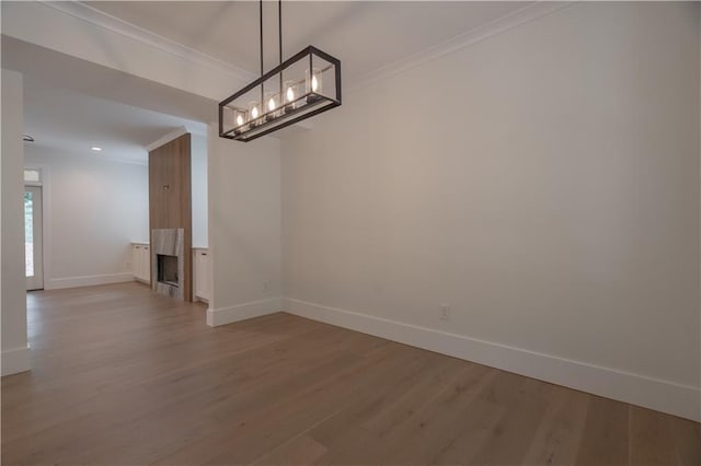 unfurnished dining area featuring ornamental molding, a fireplace, and hardwood / wood-style floors