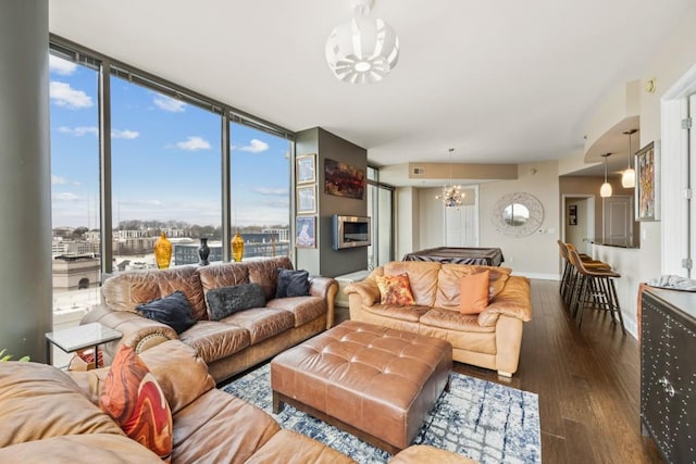 living area featuring a wall of windows, wood finished floors, baseboards, and a chandelier