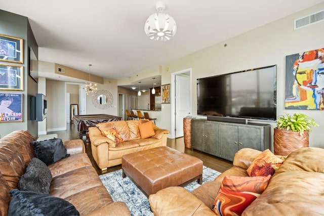 living area with wood finished floors, visible vents, and a chandelier