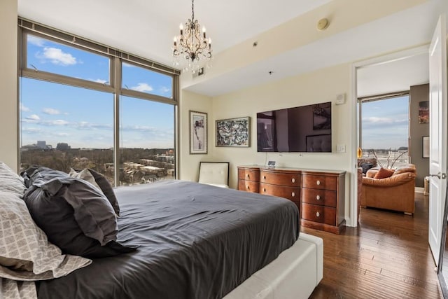 bedroom featuring dark wood finished floors, floor to ceiling windows, and a notable chandelier