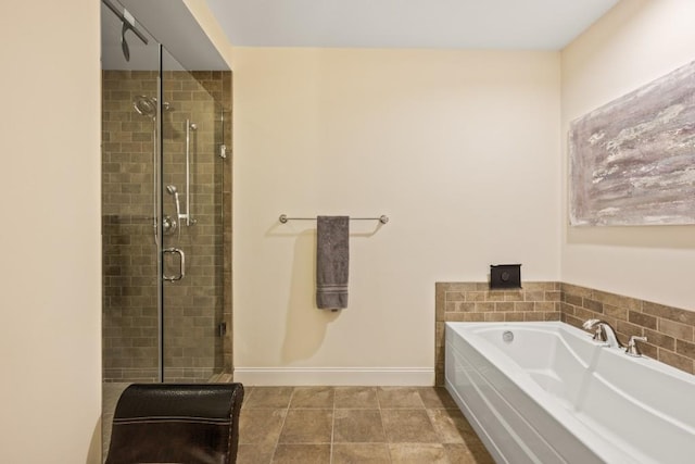 bathroom with a bath, a shower stall, and baseboards