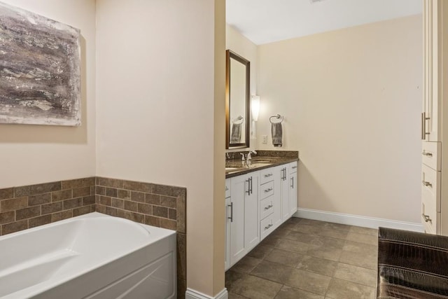 full bath featuring vanity, a bath, and baseboards