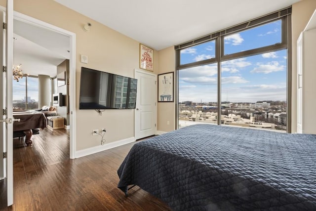 bedroom with a wall of windows, baseboards, and wood finished floors