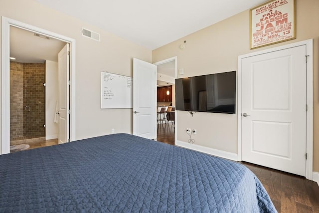 bedroom with wood finished floors, visible vents, ensuite bathroom, and baseboards