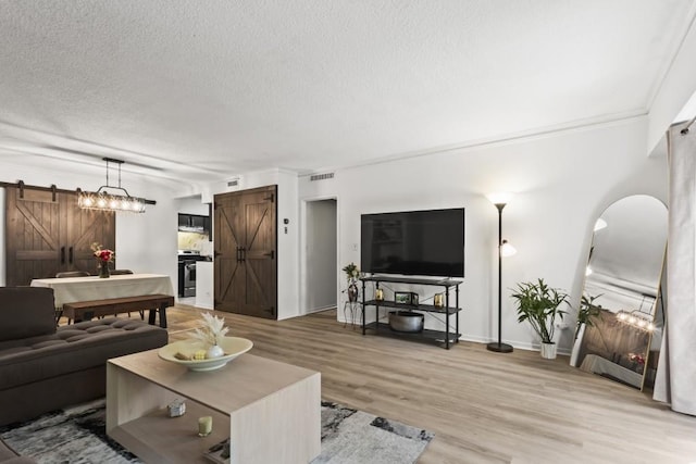 living room with a barn door, ornamental molding, hardwood / wood-style flooring, and a textured ceiling