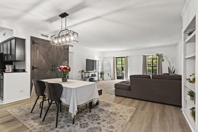 dining room with ornamental molding, light hardwood / wood-style flooring, and a textured ceiling