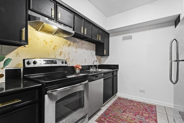 kitchen with dark stone counters, appliances with stainless steel finishes, sink, and light tile patterned floors