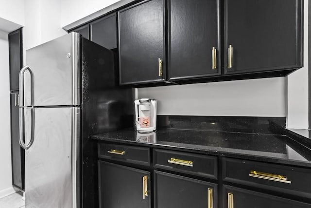 kitchen featuring dark stone counters and stainless steel refrigerator