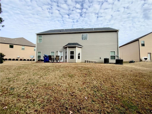 rear view of property with cooling unit and a yard