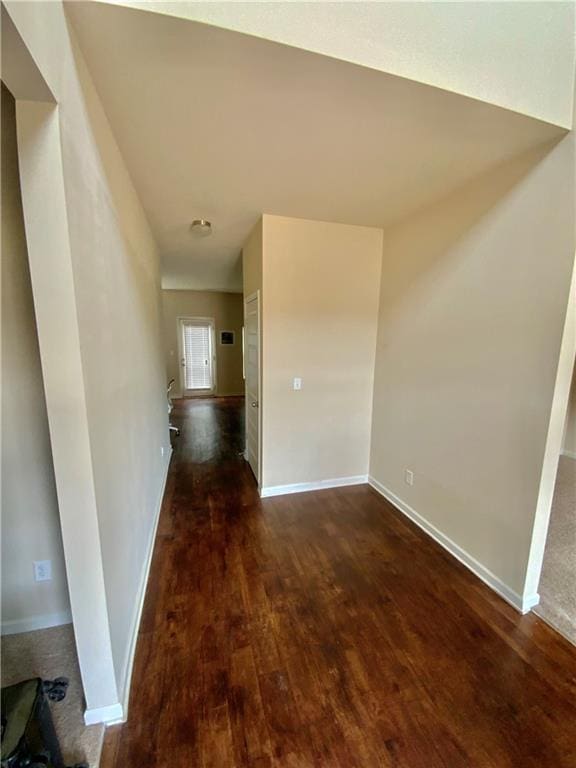 hall with baseboards and dark wood-type flooring