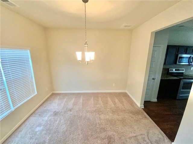 unfurnished room featuring an inviting chandelier, carpet, visible vents, and baseboards