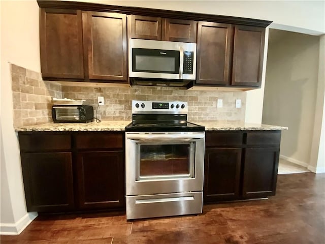 kitchen featuring appliances with stainless steel finishes, baseboards, dark brown cabinets, and decorative backsplash