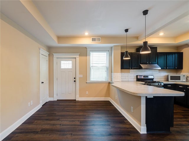 689 Berne St SE, Atlanta, GA 30312 - kitchen with stainless steel gas range oven, white microwave, under cabinet range hood, light countertops, and dark wood-style floors