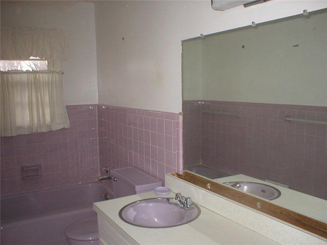 bathroom featuring toilet, tile walls, a bath, and vanity