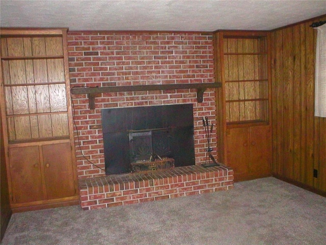 unfurnished living room featuring wood walls, a textured ceiling, carpet, and a brick fireplace