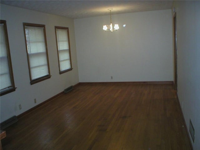 unfurnished room with a chandelier and dark hardwood / wood-style floors