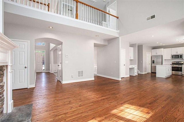 4609 Mctyre Way, Marietta, GA 30064 - unfurnished living room with dark wood-type flooring, visible vents, arched walkways, and a towering ceiling