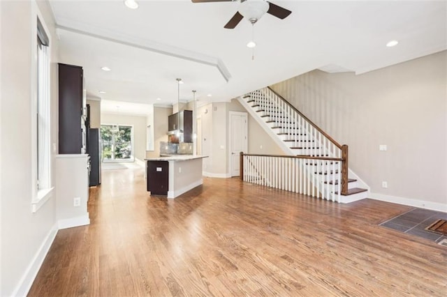 unfurnished living room with baseboards, stairs, recessed lighting, wood finished floors, and a ceiling fan