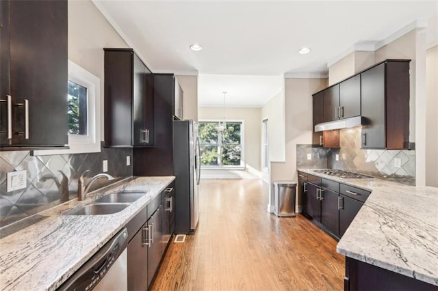 kitchen featuring light stone counters, stainless steel appliances, a sink, under cabinet range hood, and light wood-type flooring