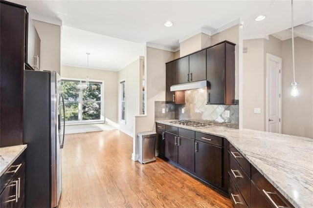 kitchen with light wood-style flooring, stainless steel appliances, dark brown cabinetry, under cabinet range hood, and backsplash