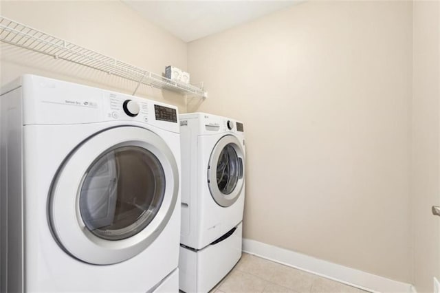 laundry area with laundry area, light tile patterned floors, baseboards, and washer and clothes dryer