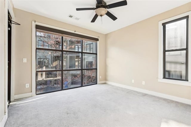 carpeted empty room with visible vents, baseboards, and a ceiling fan