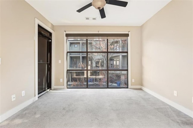 carpeted empty room featuring visible vents, baseboards, and ceiling fan