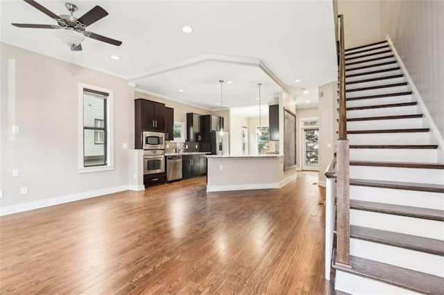 unfurnished living room featuring baseboards, ceiling fan, stairs, recessed lighting, and wood finished floors