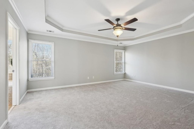 empty room with a raised ceiling, visible vents, light carpet, and baseboards