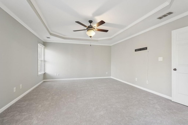 spare room with ornamental molding, a raised ceiling, visible vents, and baseboards